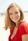 A blonde woman on a beach wearing a red top