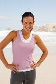 A young brunette woman by the sea wearing sports clothes