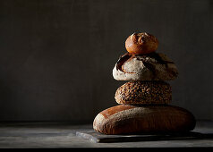 Three different breads and a bread roll, stacked