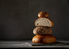 Three breads and a bread roll, stacked against a dark background