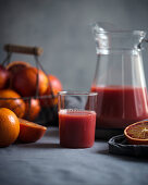 Blood orange juice in a glass jug with fresh fruit