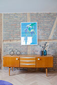 Sideboard below blue poster on brick wall of living room