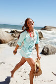 A brunette woman wearing a light-blue beach dress by the sea