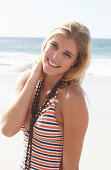 Junge blonde Frau in gestreiftem Badeanzug am Strand