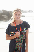 A young blonde woman with necklace wearing a beach dress