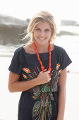 A young blonde woman with necklace wearing a beach dress