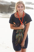 A young blonde woman with necklace wearing a beach dress