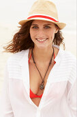 Brünette Frau mit Hut in rotem Bikinioberteil und weißer Bluse