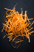 A pile of carrot peel on a black background