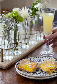 A brunch table with a lemon tart, flowers and champagne with orange juice