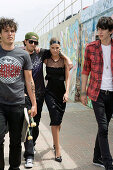 A young woman wearing a black party dress with young men at a skatepark