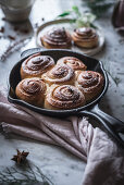 Frying pan with tasty fresh cinnamon rolls placed near napkin on marble tabletop