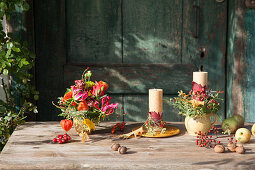 Herbstlich dekorierte Kerzen und Blumenschmuck
