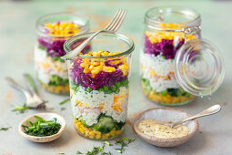 Layered salads with vegetables, ham, eggs and mayonnaise sauce in glasses