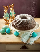 A Bundt cake dusted with icing sugar with Easter decorations