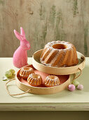 A Bundt cake and mini Bundt cakes dusted with icing sugar with Easter decorations