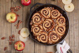 Apple pecan sticky buns with caramel sauce in a cast iron pan