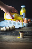 Selbstgemachter Eierlikör wird aus Flasche in Waffelbecher gegossen