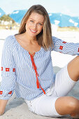 Blonde Frau in blau-weiß gestreifter Bluse und kurzer Hose am Strand