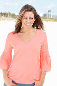 A young woman on a beach wearing an apricot blouse