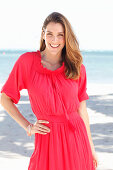 Brünette Frau in rotem Kleid am Meer