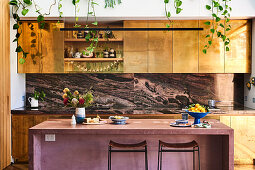 Küche mit goldfarbenen Fronten und mauvefarbener Frühstücksbar