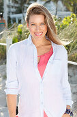 A young woman outside wearing a pink top and a light shirt blouse