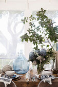 A wooden table laid for Christmas with a balloon bottle and floral decorations