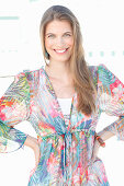 A young woman by the sea wearing a colourful beach dress