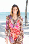 Brünette Frau in buntem Strandkleid am Meer