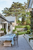 Antique stone table with metal chairs on terrace by the house