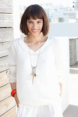 A brunette woman wearing a white long-sleeved blouse