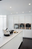 White designer kitchen with island counter and fitted appliances
