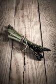 Green asparagus spears tied together on a wooden background