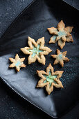 Vegane Mürbeteigkekse in Schneeflockenform mit Vanille-Sojaquark-Creme und blauem Puderzucker