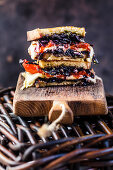 A sandwich with grilled vegetables (peppers, red cabbage, tomatoes) and cheese
