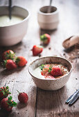 Bowl with sweet porridge garnished with spices and strawberry