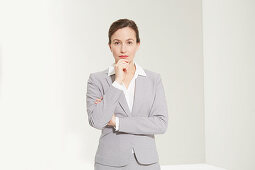 A business woman holding her index finger to her chin