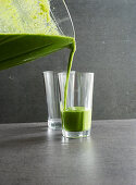 Green smoothies being poured into glasses