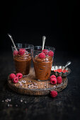 Two glasses of vegan chocolate mousse decorated with fresh raspberries