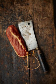 A cleaver and bacon on a wooden background