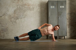 A young man performing a side plank with hips raised