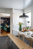 Long table with bench and fitted cupboards in white kitchen