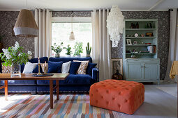 Dark blue sofa and orange pouffe in vintage-style living room