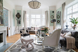 Stylish seating around round table in living room with window bay