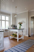 Island counter in white, spacious country-house kitchen with windowseat