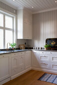 White, spacious country-house kitchen with wood-panelled walls