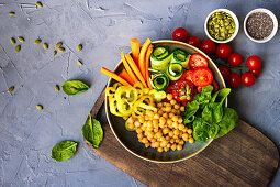 Buddha bowl with chickpea, baby spinach and other organic vegetables on concrete background