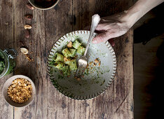 Hands taking bowl of delicious pasta paccheri with tasty kale pesto and ground peanuts