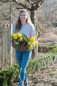 Woman carries basket of primroses and rosemary